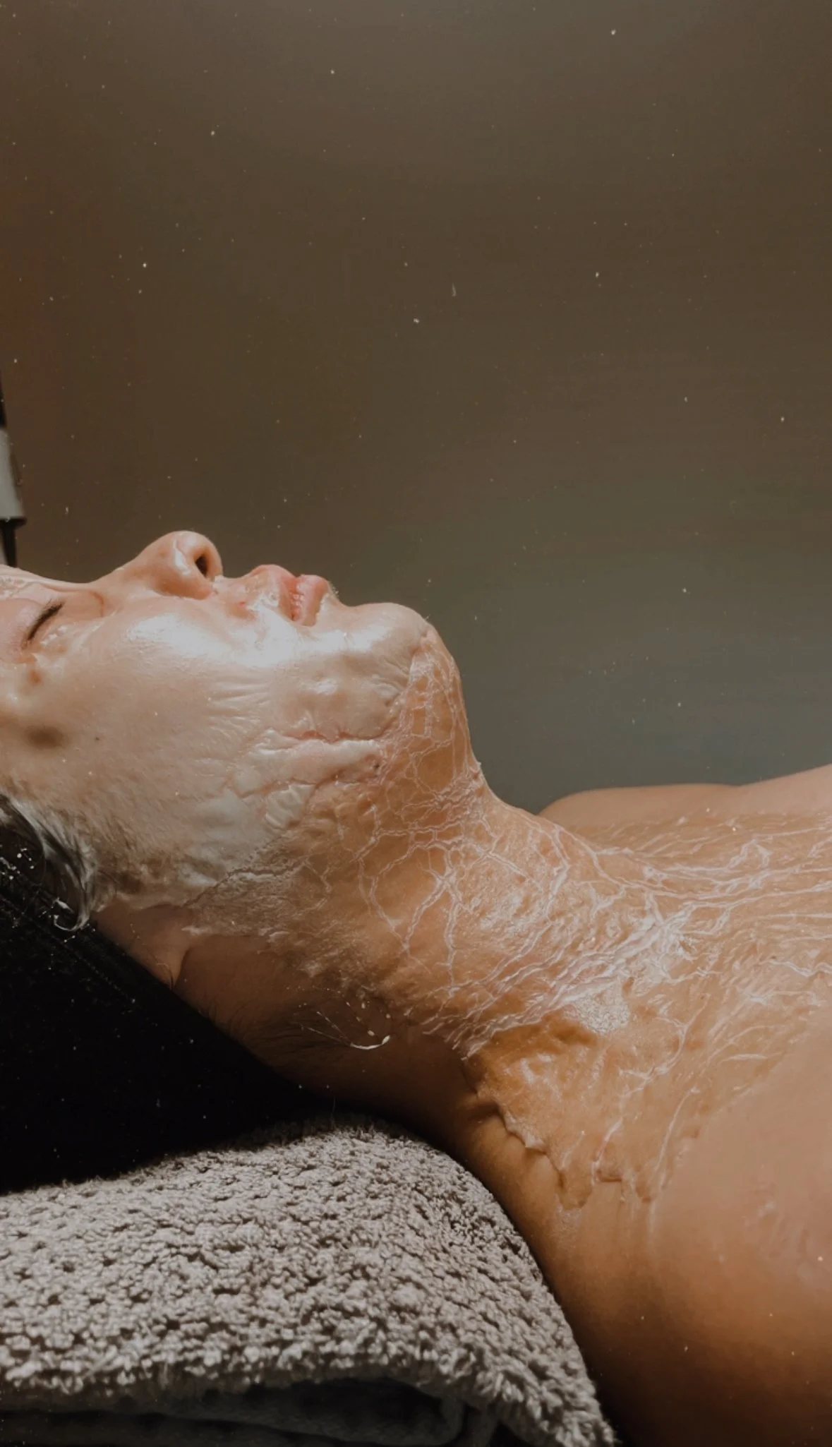 Person receiving a DMK Intense Neck Lift facial treatment in a spa setting.