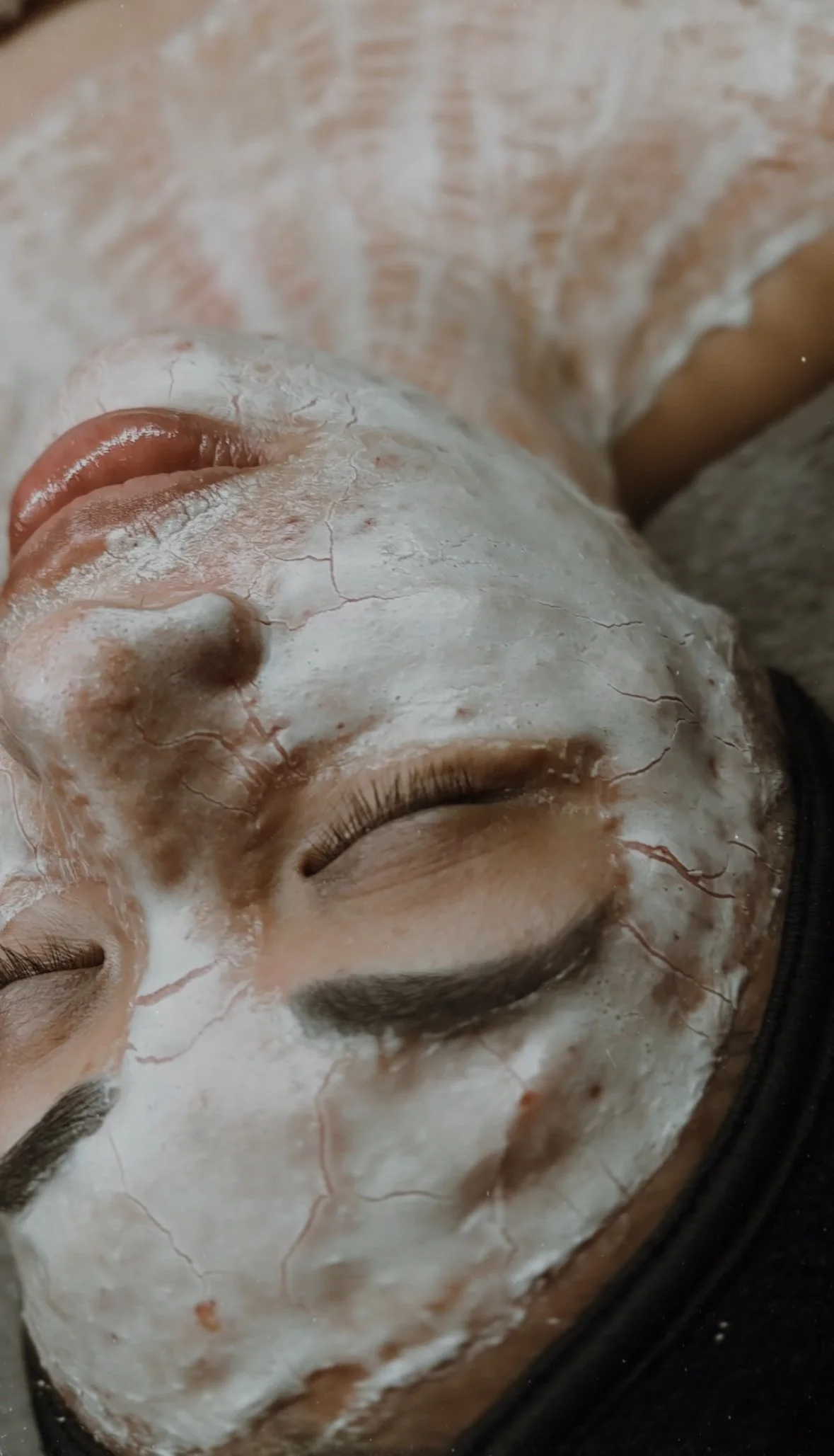 Person DMK enzyme face mask lying down, eyes closed.