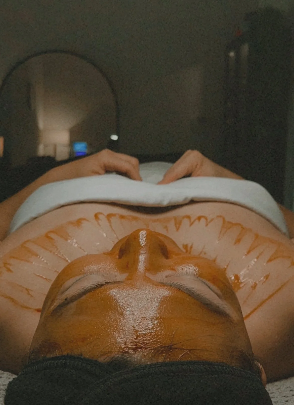 Person receiving a facial treatment with osmosis facial infusion serum in a spa setting, hands resting on chest.