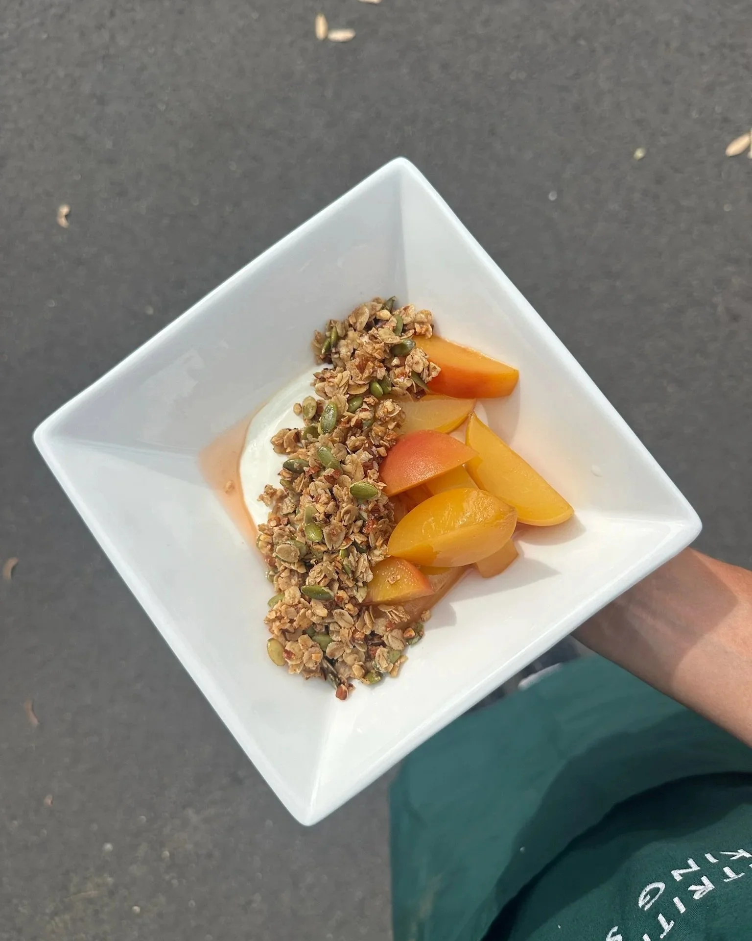 Poached peaches with honey labneh and oat crumble in a white bowl — healthy protein-rich dessert recipe by Grams of Health dietitians