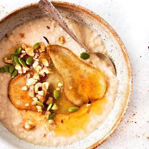 Honey and pear porridge in a bowl with roasted pear and toasted pepitas — healthy high-protein breakfast recipe by Grams of Health dietitians