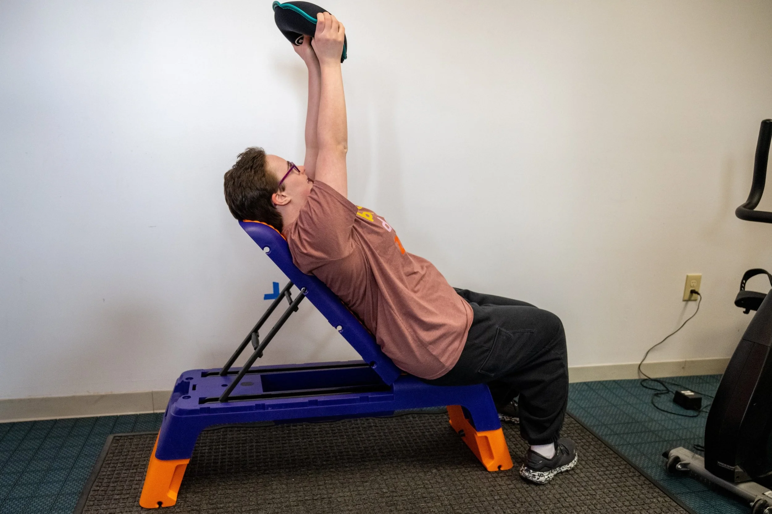Person using an incline bench and doing chest press with a sandbag