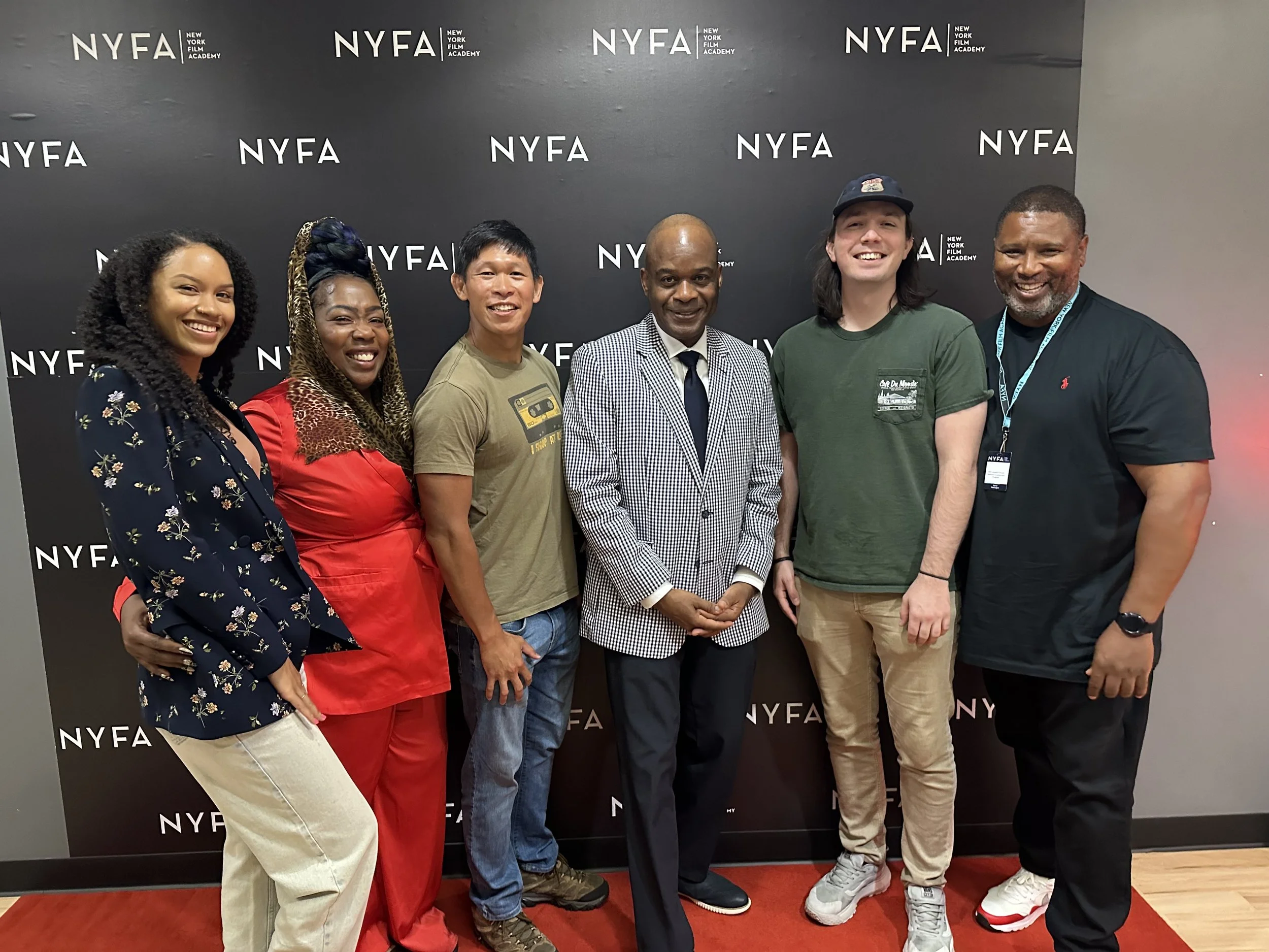 Group of six diverse individuals standing in front of a NYFA backdrop, smiling at the camera.