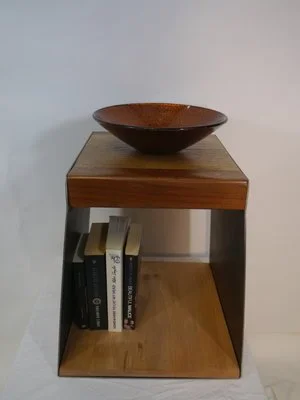 Une étagère en bois avec un bol en céramique dessus et quelques livres en dessous.