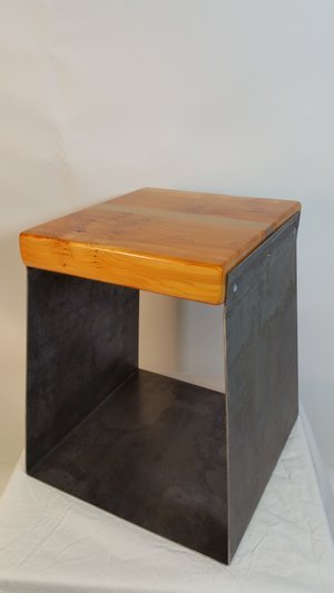 Table en bois avec structure en métal noire, placée contre un mur blanc.
