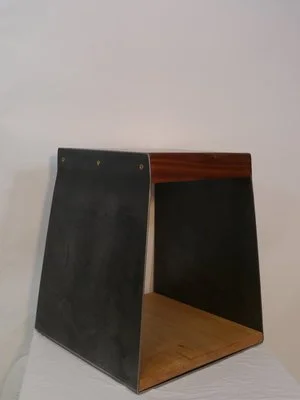 Un meuble en bois avec des côtés en métal noir, ouvert d'un côté, placé contre un mur blanc.