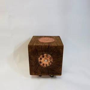 Un cube en bois avec un trou circulaire contenant une pièce de monnaie ou un jeton.