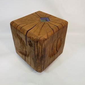 Une petite table ou un tabouret en bois avec une surface carrée, montrant des craquelures et des motifs de bois.»