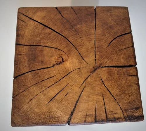 Une planche de bois carrée avec des fissures visibles, montrant les anneaux de croissance du bois.