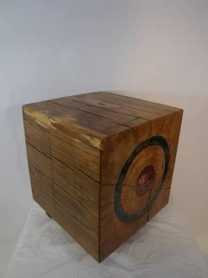 Un cube en bois avec un cercle noir et un centre rose peint sur une face.