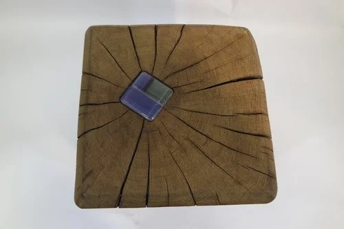 Une pièce de bois carrée avec des fissures et une petite boîte de moquette transparente sur le dessus.