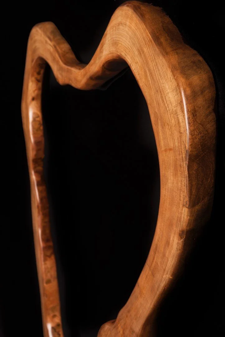 Vue d'une sculpture en bois de forme incurvée, sur fond noir