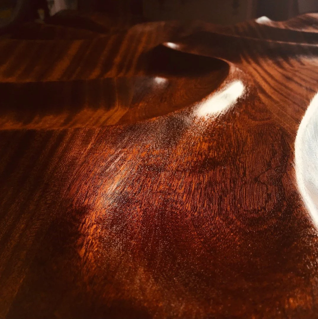 Un gros plan de la surface d'un meuble en bois foncé, avec des détails de la texture du bois, montrant des reflets et des grains.