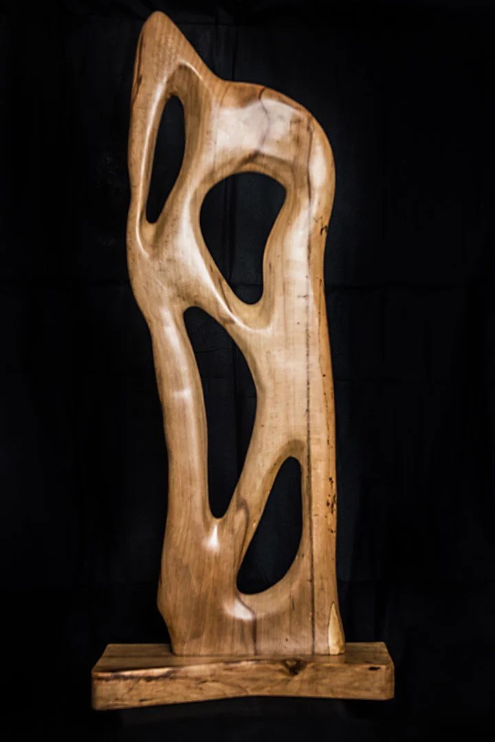 Sculpture en bois avec formes abstraites, montée sur une base en bois.