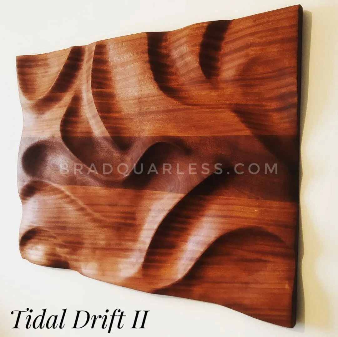 Une sculpture en bois intitulée 'Tidal Drift II', avec des formes ondulantes et texturées sculptées dans le bois, inclinée sur un mur blanc.