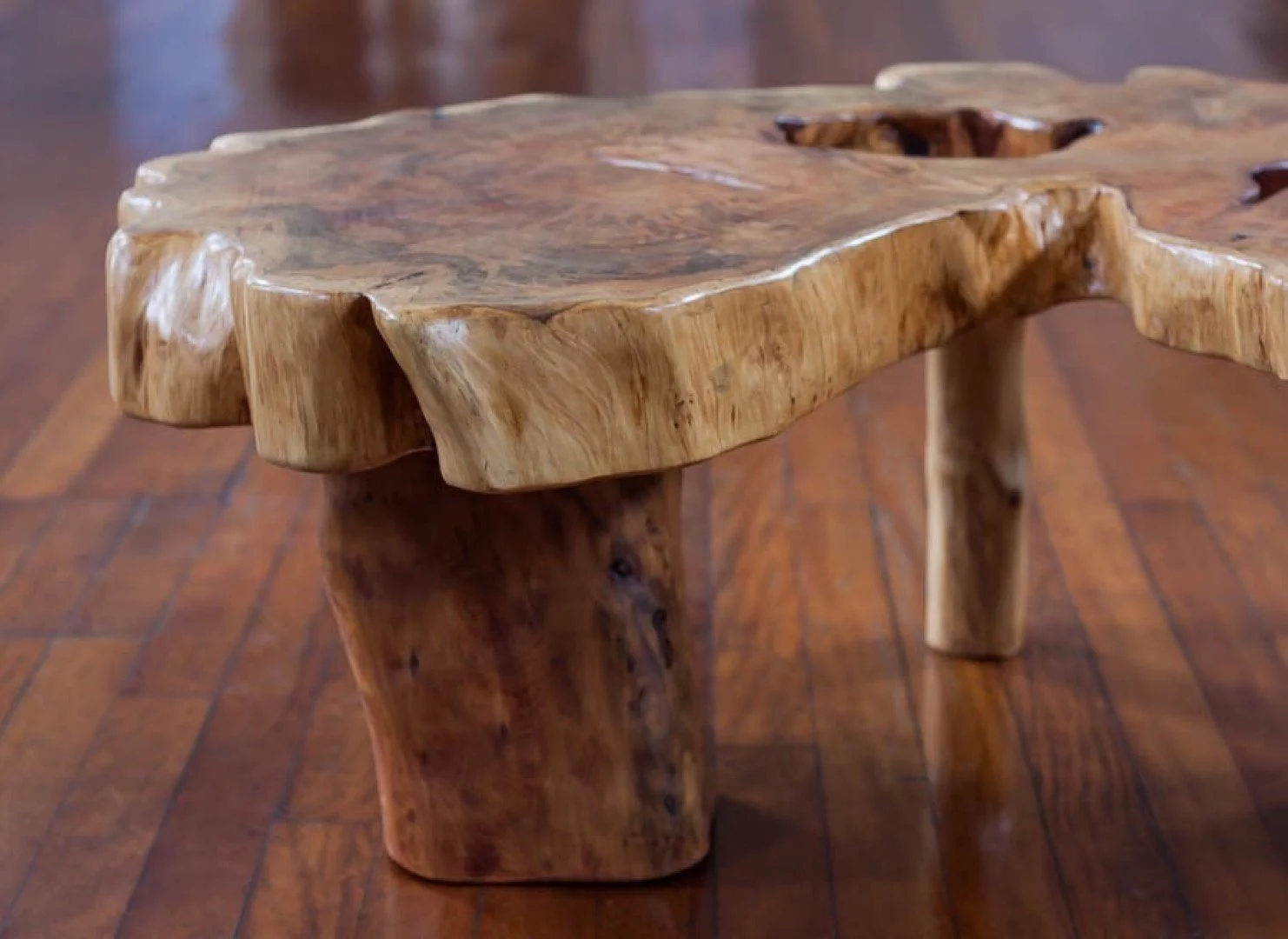 Table en bois brut avec un design naturel et organique, placé sur un sol en bois.
