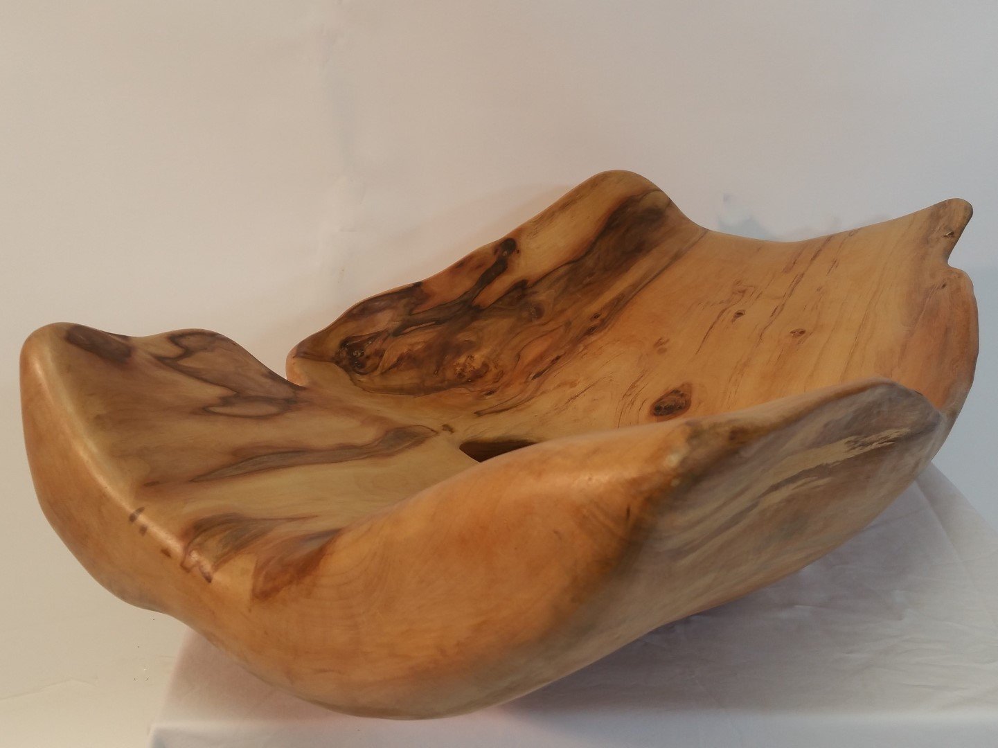 Une coupe en bois sculpté avec des motifs naturels, sans poignées, utilisée comme objet décoratif ou pour servir.
