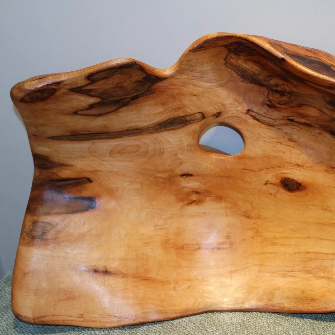 Une assiette en bois sculptée avec un trou au centre, montrant les grain et texture naturelles du bois.