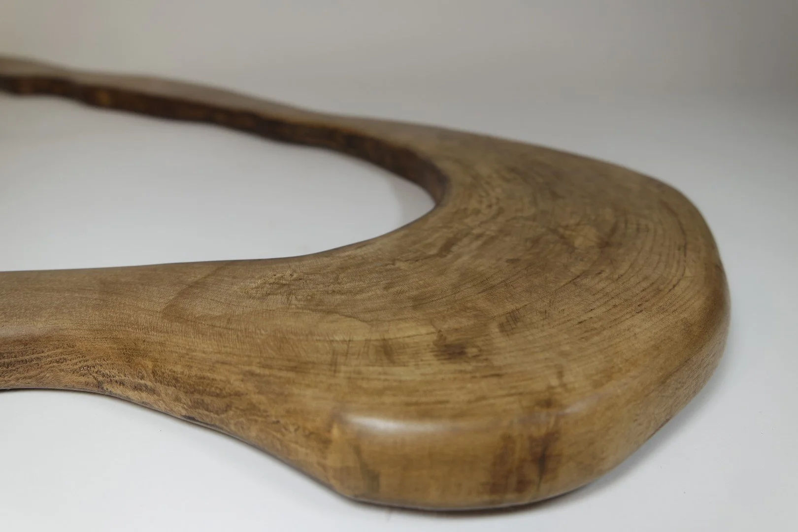 Une cuillère en bois avec une finition lisse et une courbe élégante, sertie sur un fond blanc.