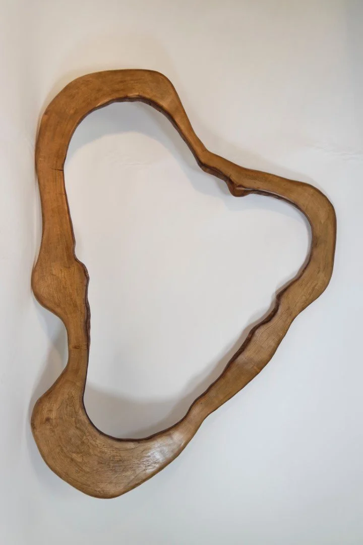 Une pièce de bois sculptée en forme de cœur ou de tracé abstrait, suspendue au mur.