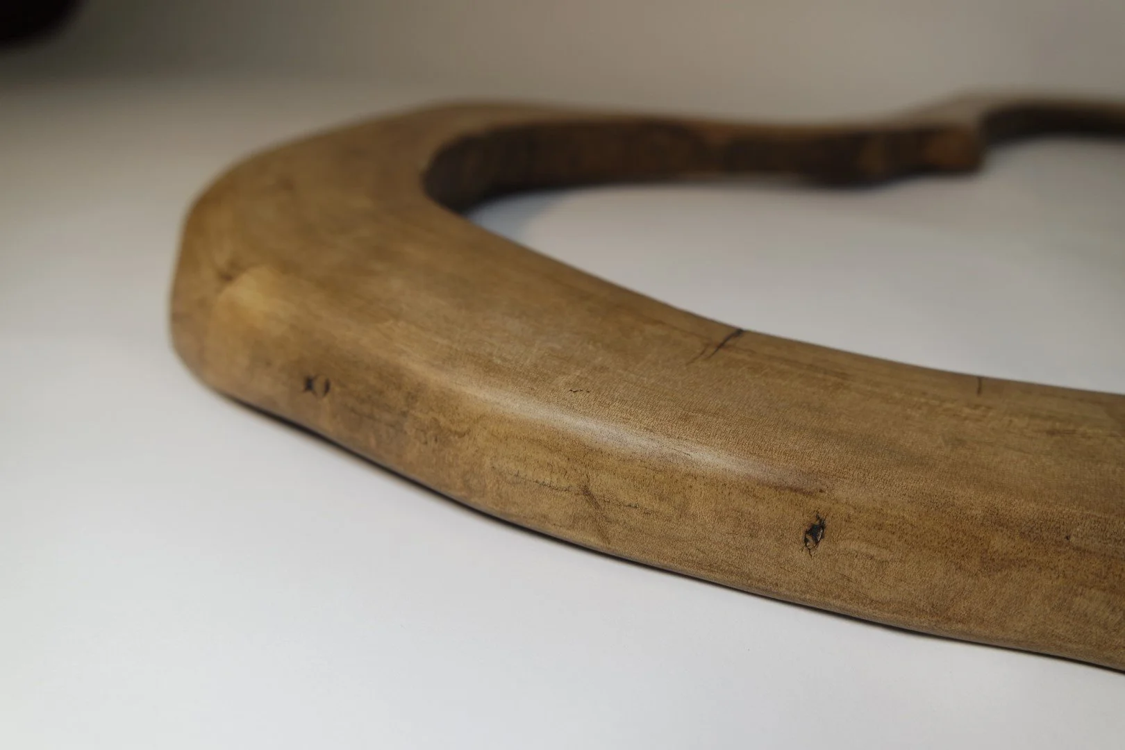 Une boucle d'oreille en bois ronde avec une surface lisse et une finition naturelle, posée sur une surface blanche.