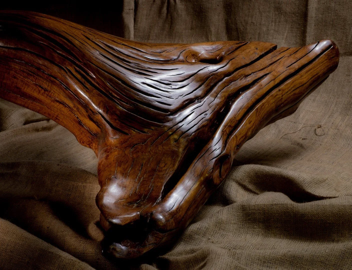 Sculpture en bois représentant un loup abstrait sur un tissu brun.