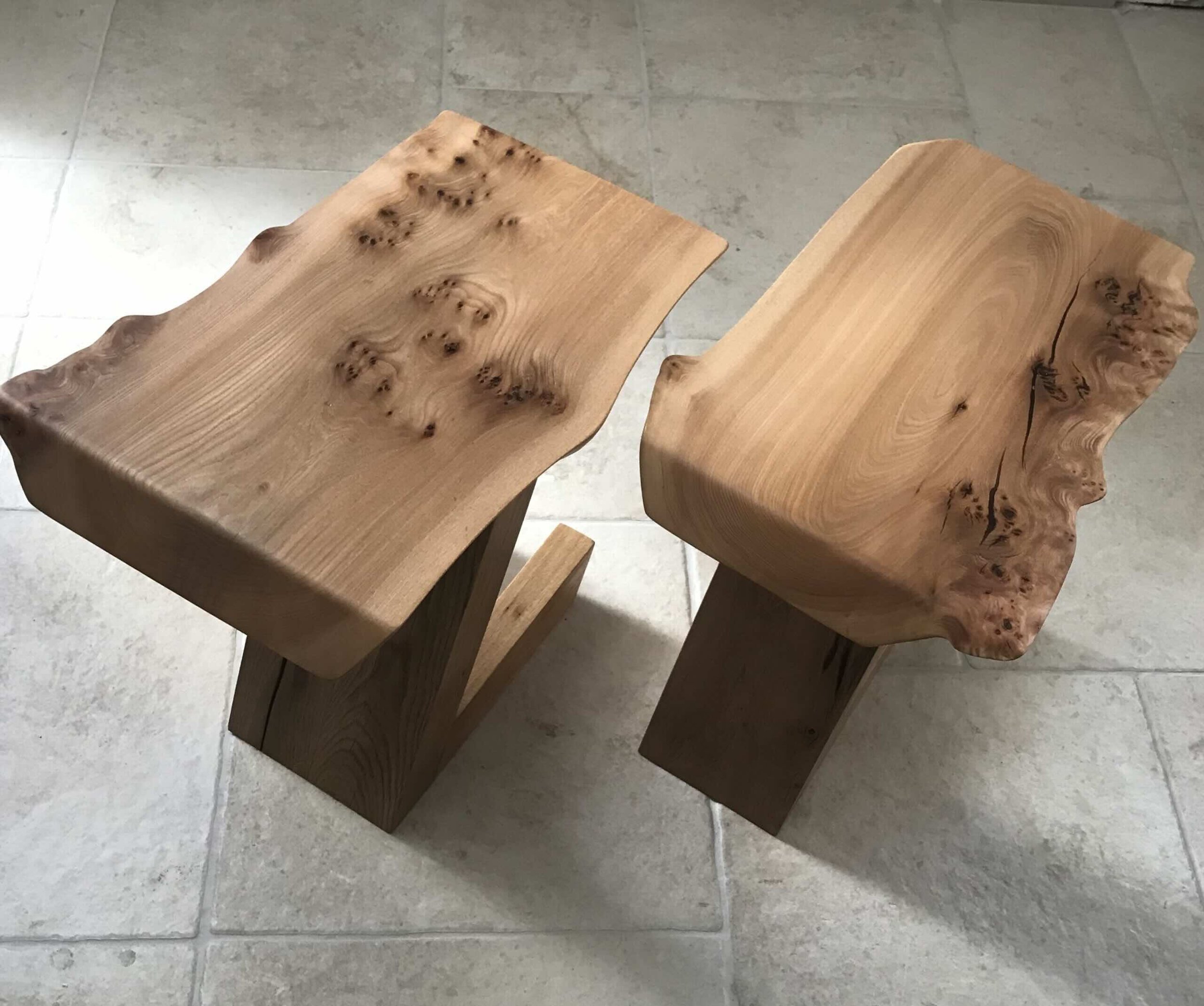Deux meubles en bois brut avec des surfaces naturelles, exposés sur un sol en carreaux gris.