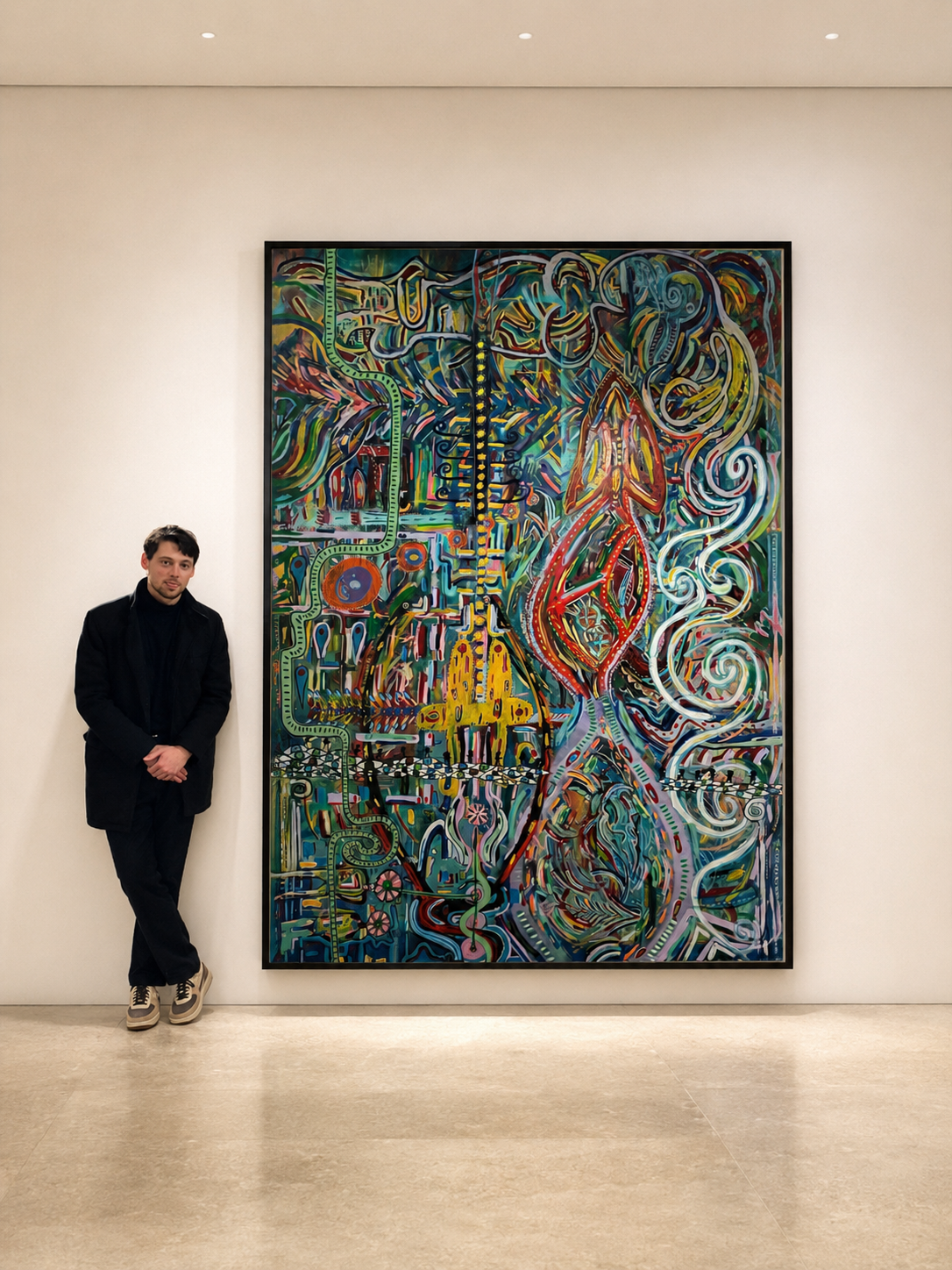 A man stands next to one of Roland’s colorful paintings on display at an art museum exhibition.