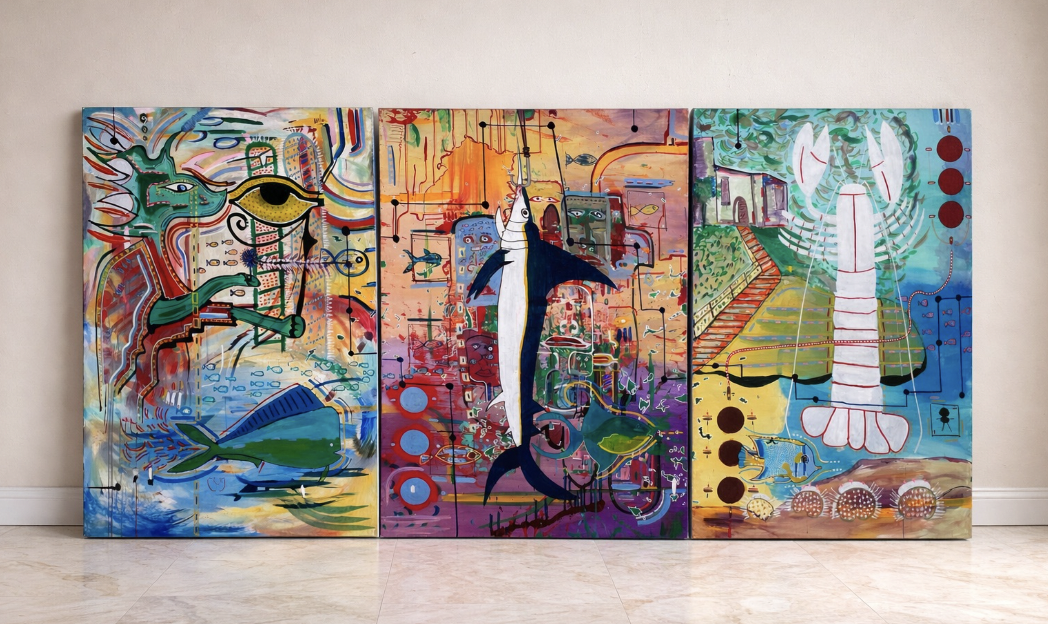 Colorful abstract triptych painting featuring large eye, fish, insects, geometric shapes, and various symbols on canvases mounted on a wall.