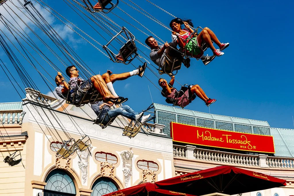 People riding a swing carousel ride at Madame Tussauds in Vienna on a sunny day.