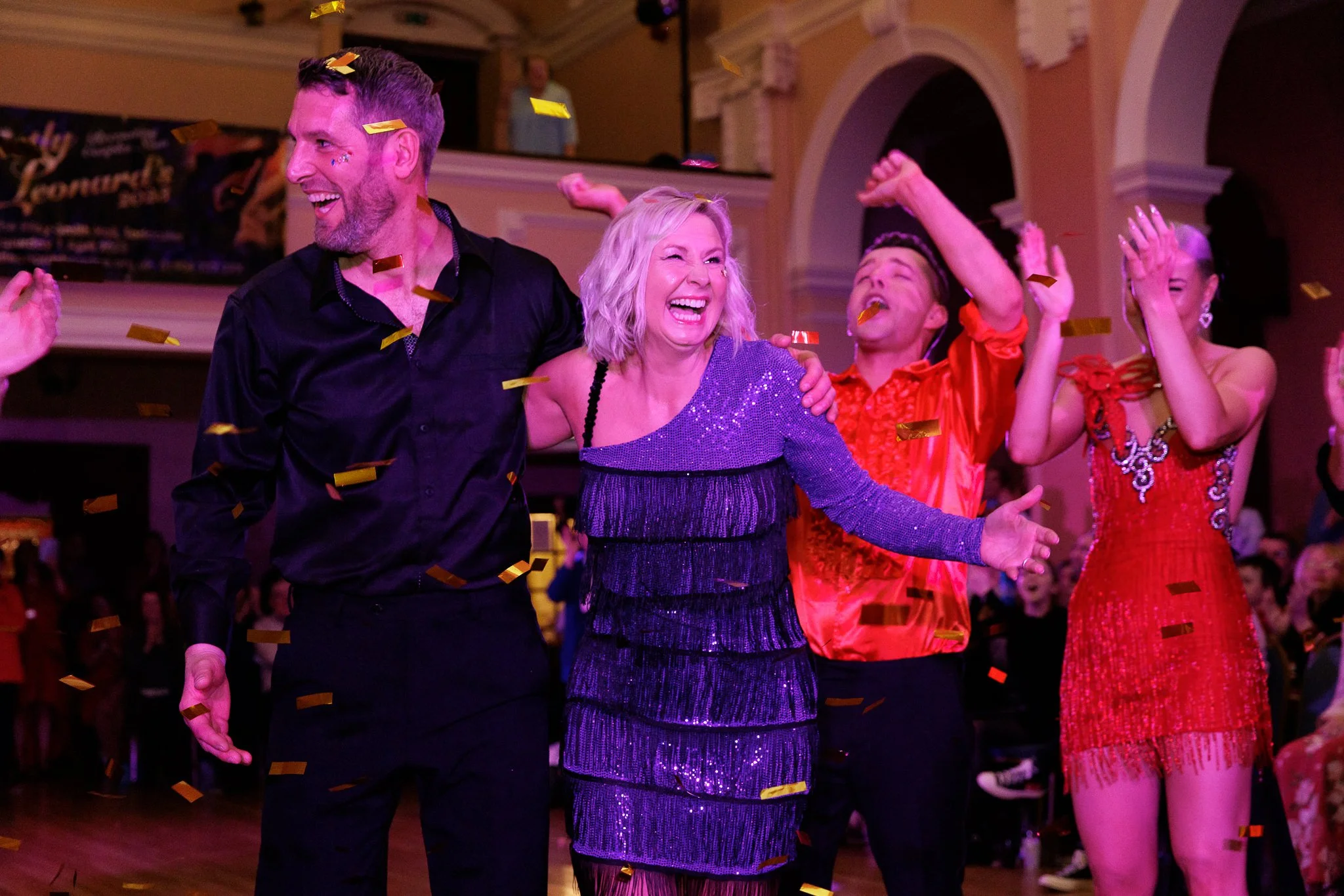 People dancing and celebrating at a party with confetti falling.