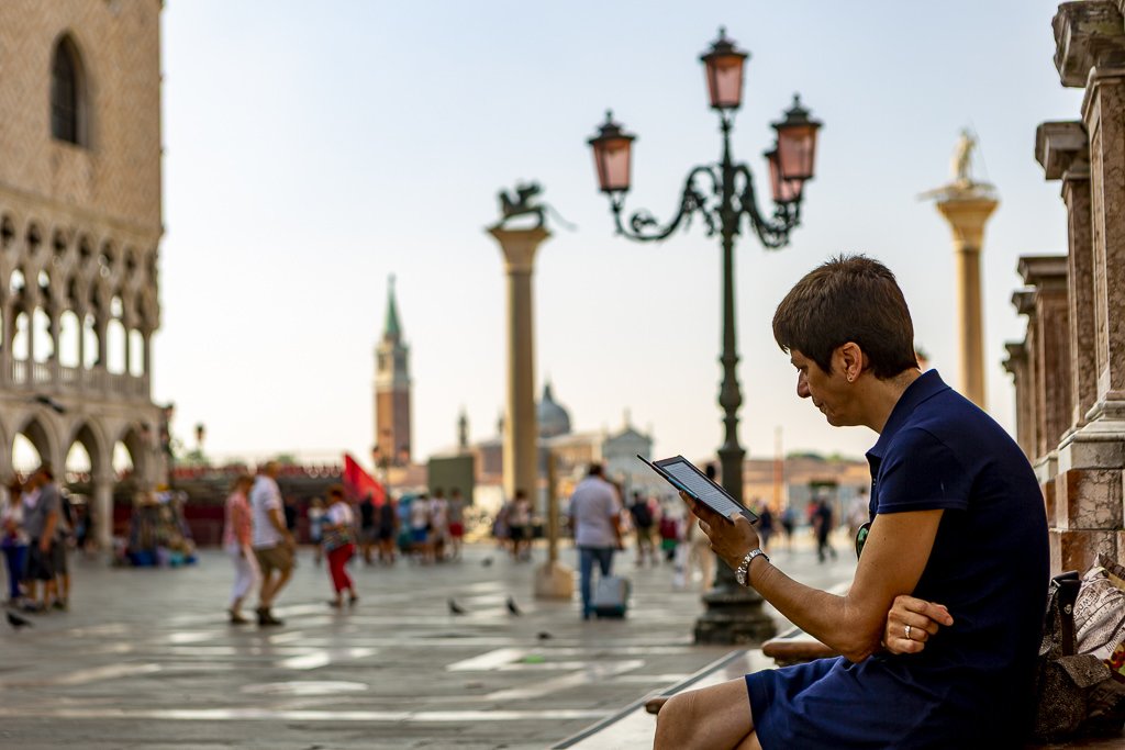 a lady taking a break to read a book in st marks square, Venice.