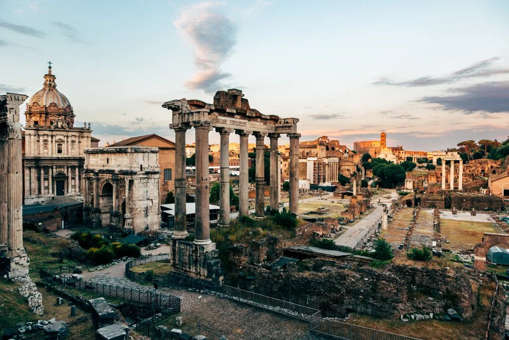Ancient ruins of Roman temples and structures in Rome, Italy, during sunset.