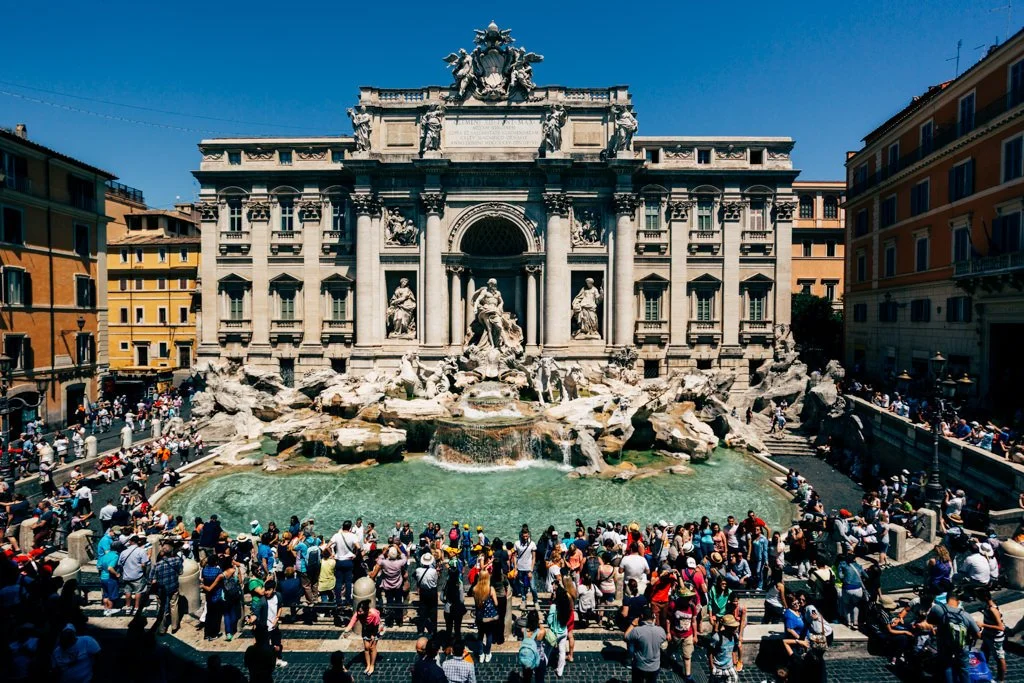 The Trevi Fountain in Rome, Italy, is a grand Baroque-style fountain with ornate sculptures and cascading water, surrounded by numerous tourists.