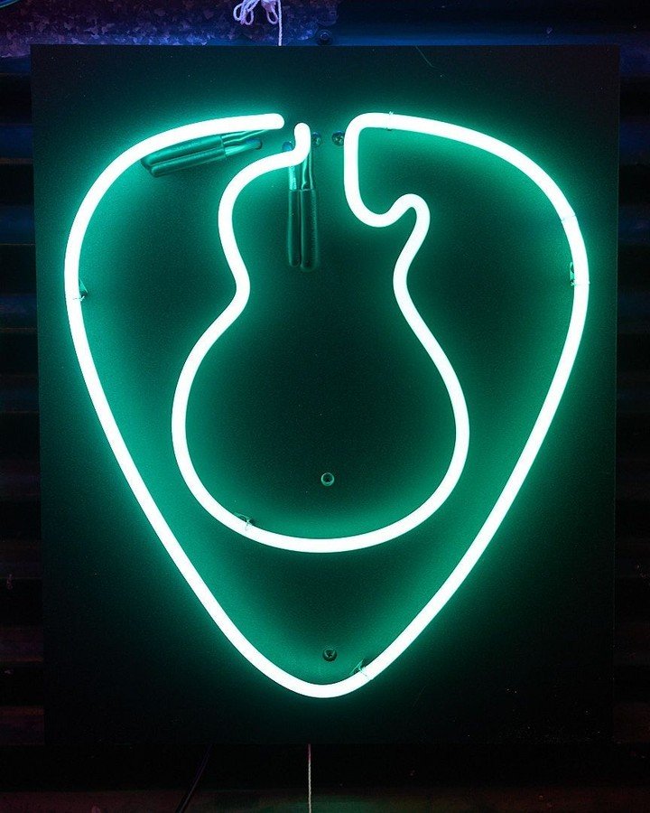 A neon guitar pick created during a workshop.
