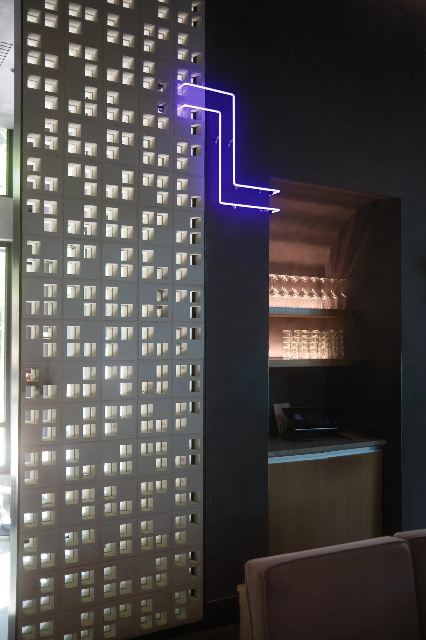 After emerging from the blocks, the neon travels down the wall like a vine, and turns into an alcove where it disappears.