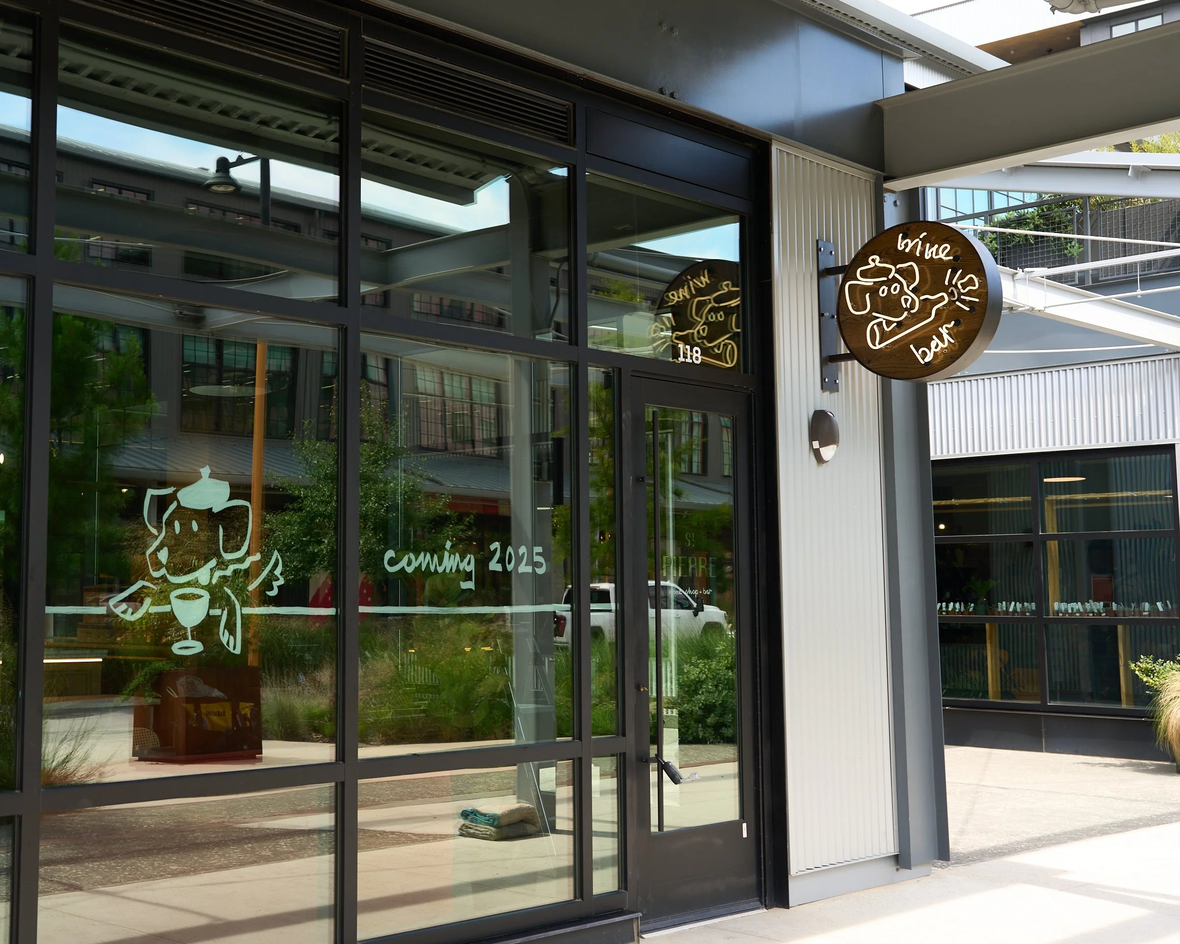 St. Pierre's facade features a double sided, flag-mount blade sign made of steel and white oak wood, stained a dark color to mimic the look of a wine barrelhead. Using warm white neon and a flasher, the cork of the wine bottle appears to pop out!