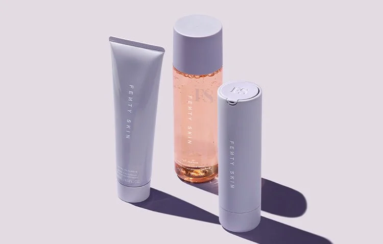 Three Fenty Skin skincare products: a tube, a bottle, and a pump container, placed on a surface with shadows.