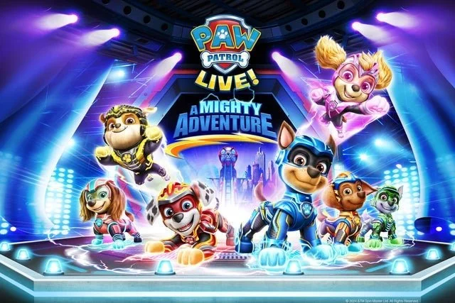 Colorful promotional poster for PAW Patrol Live! A Mighty Adventure featuring animated puppy characters on stage with vibrant lights and a cityscape backdrop.