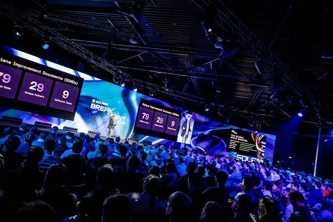 A tech conference with a group of people listening to a panelist speaker