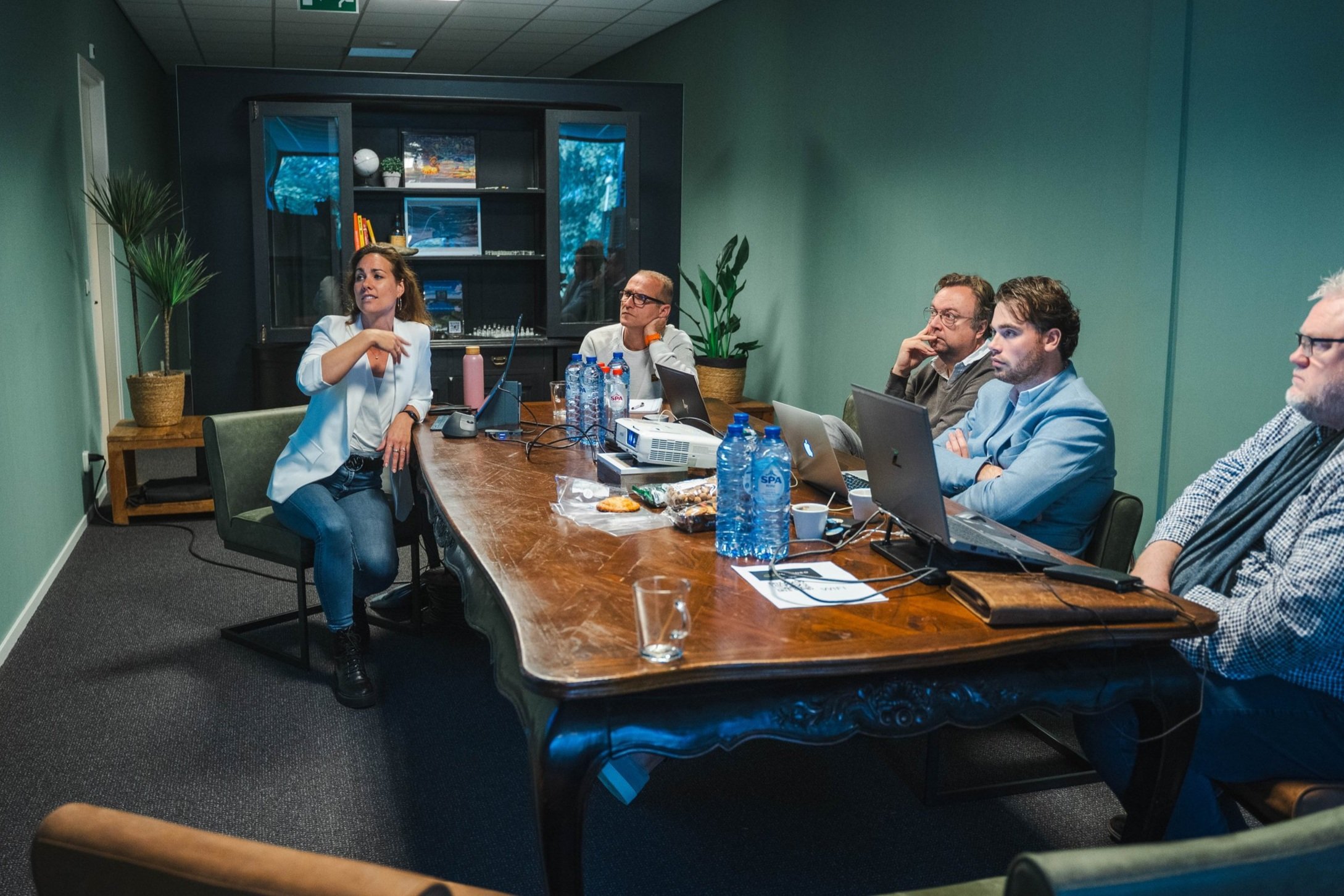 People having a meeting in a conference room with laptops and bottled water on the table.