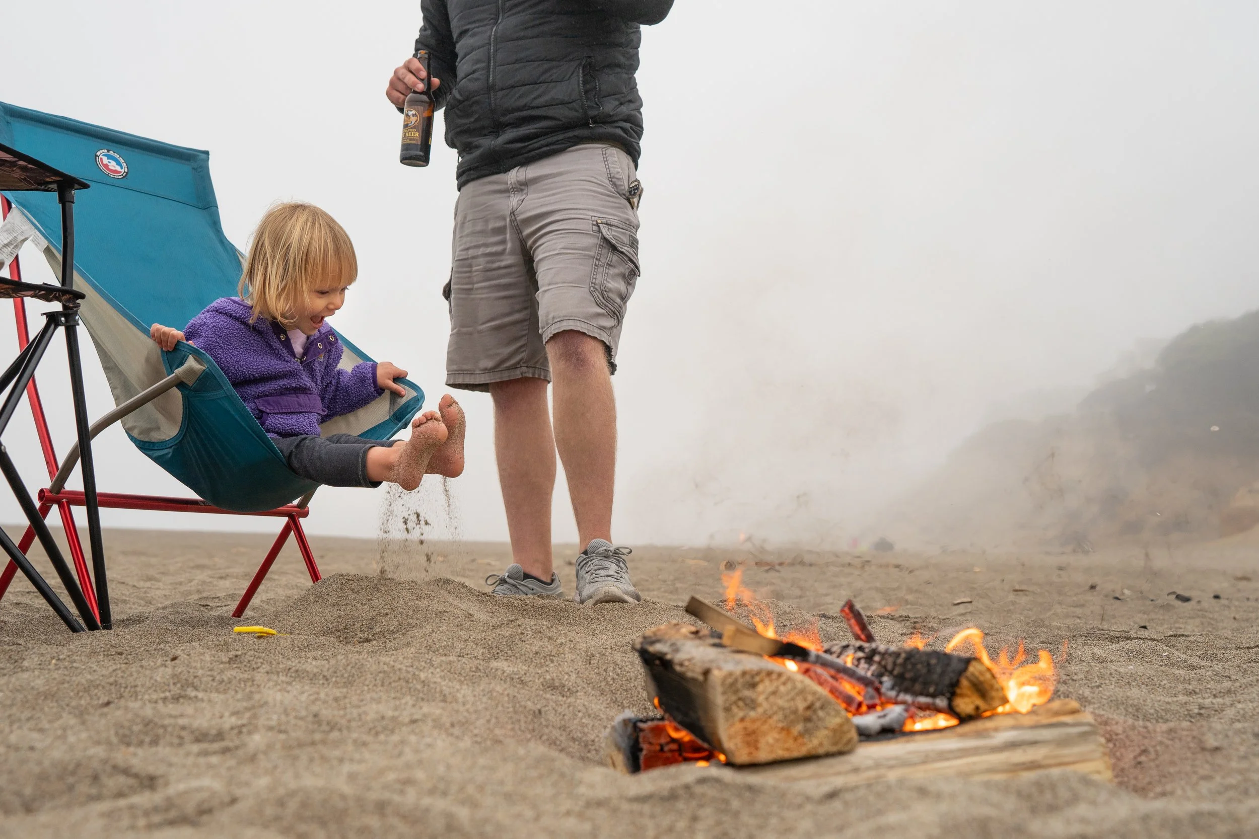 young girl playing in the sand by a campfire in lincoln city oregon