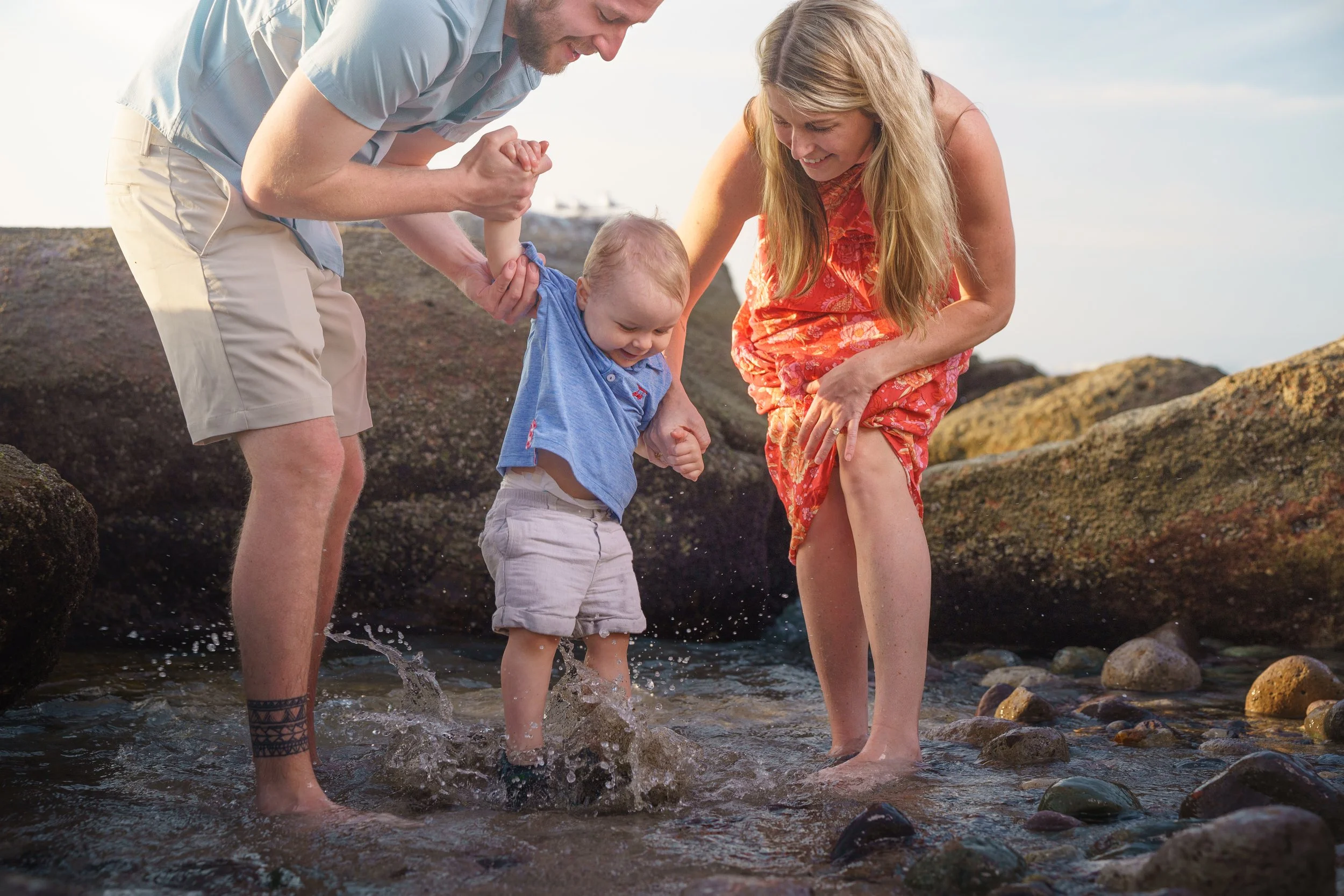 parents with their baby playing in the water at the tide pools in lincoln city oregon