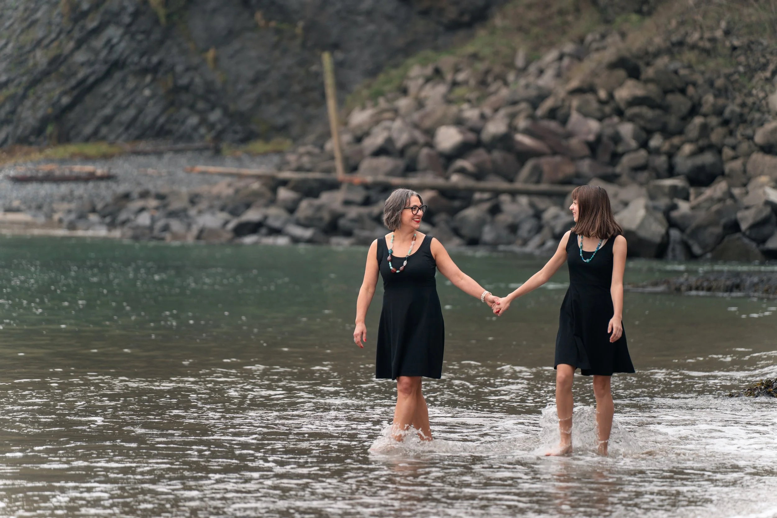 Mom and daughter walking in the water holding hands in lincoln city