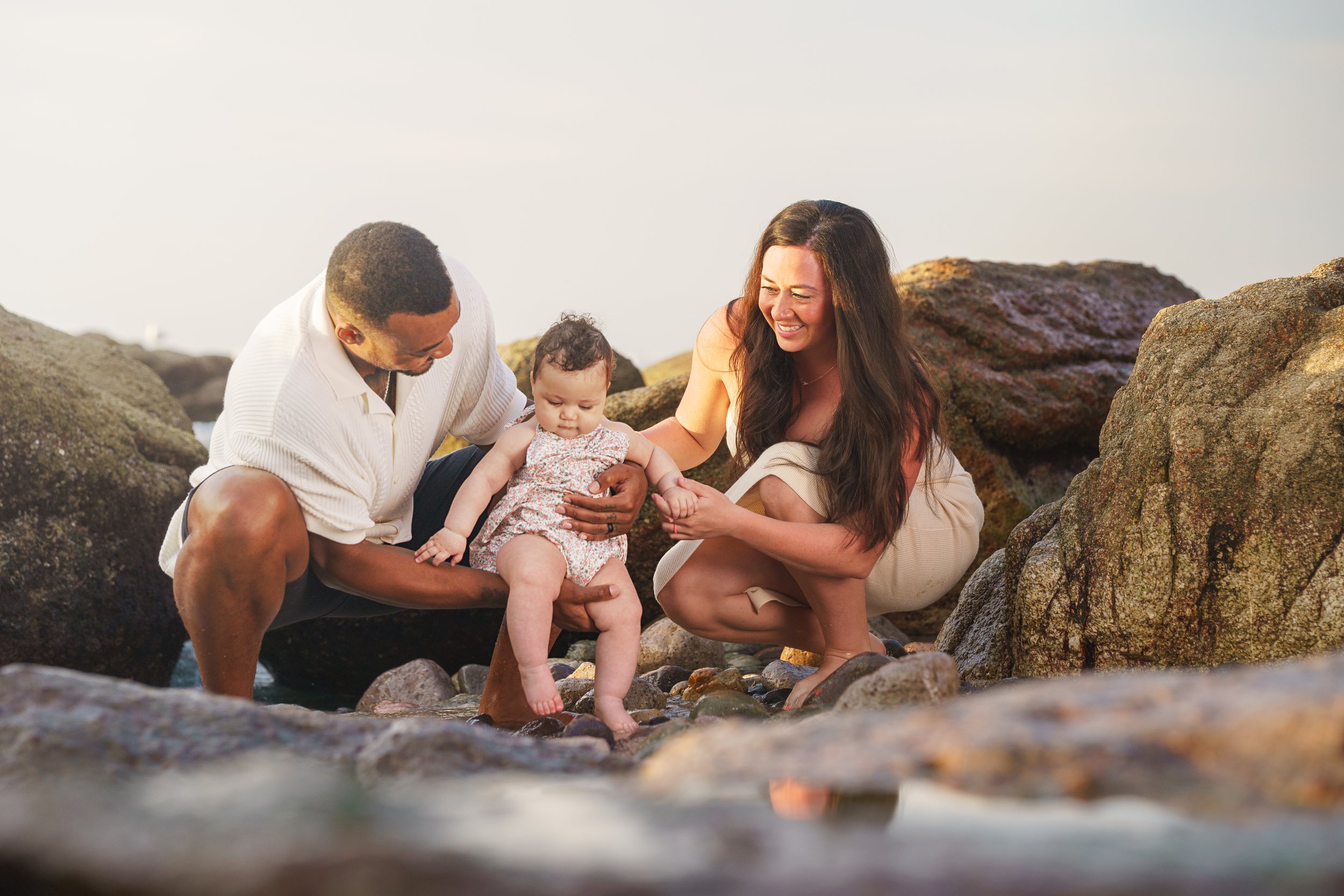 family portrait session with two parents and their baby playing in the water