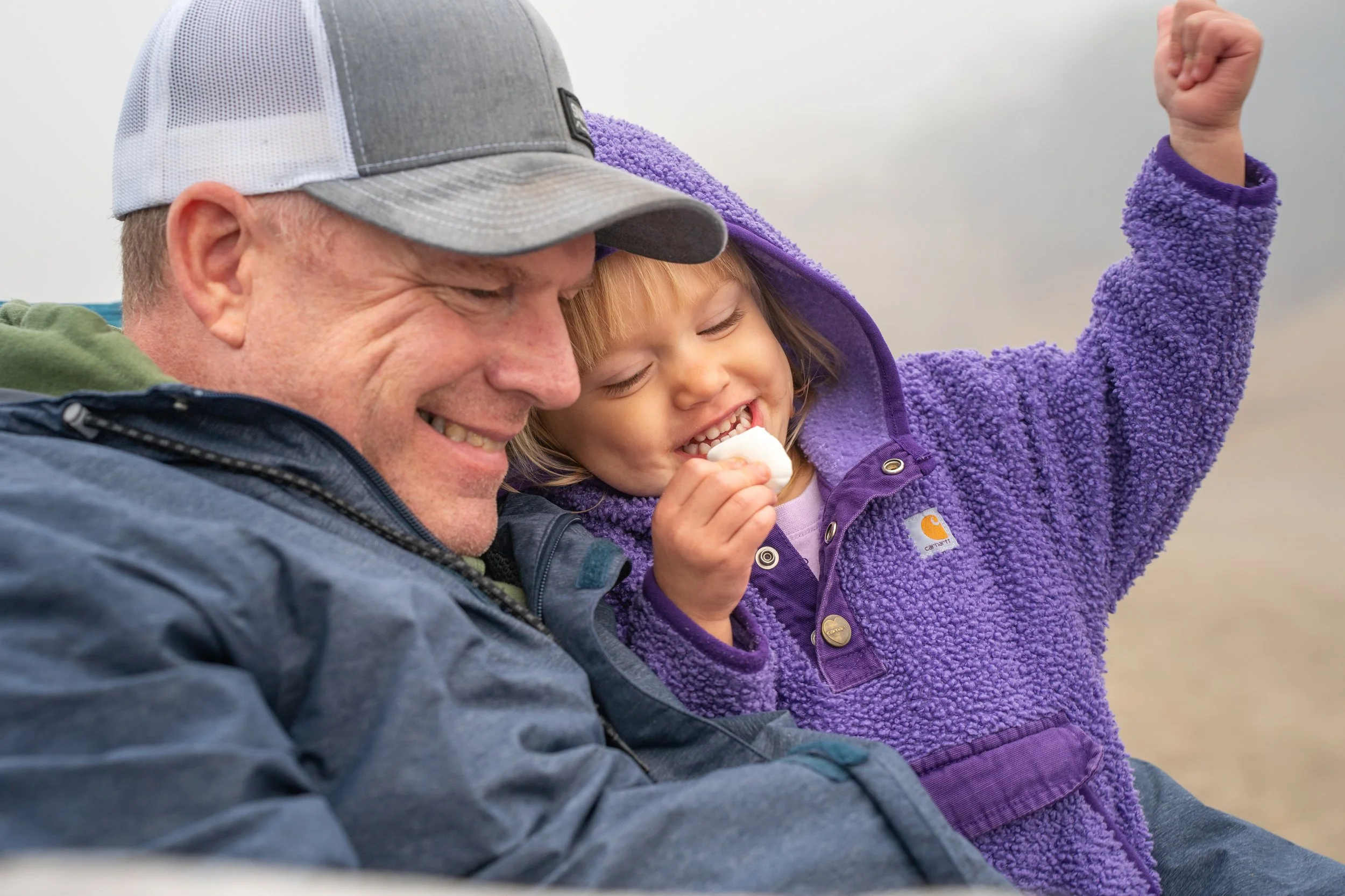 grandpa and his granddaughter eating marshmallows on the oregon coast