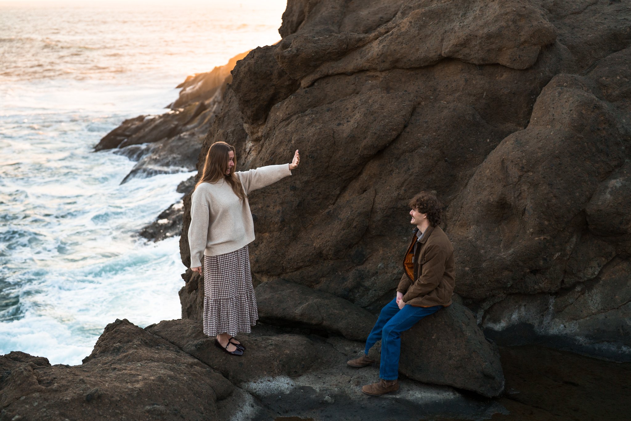 a couple sitting by the ocean, enjoying the sunset while checking out a new engagement ring!