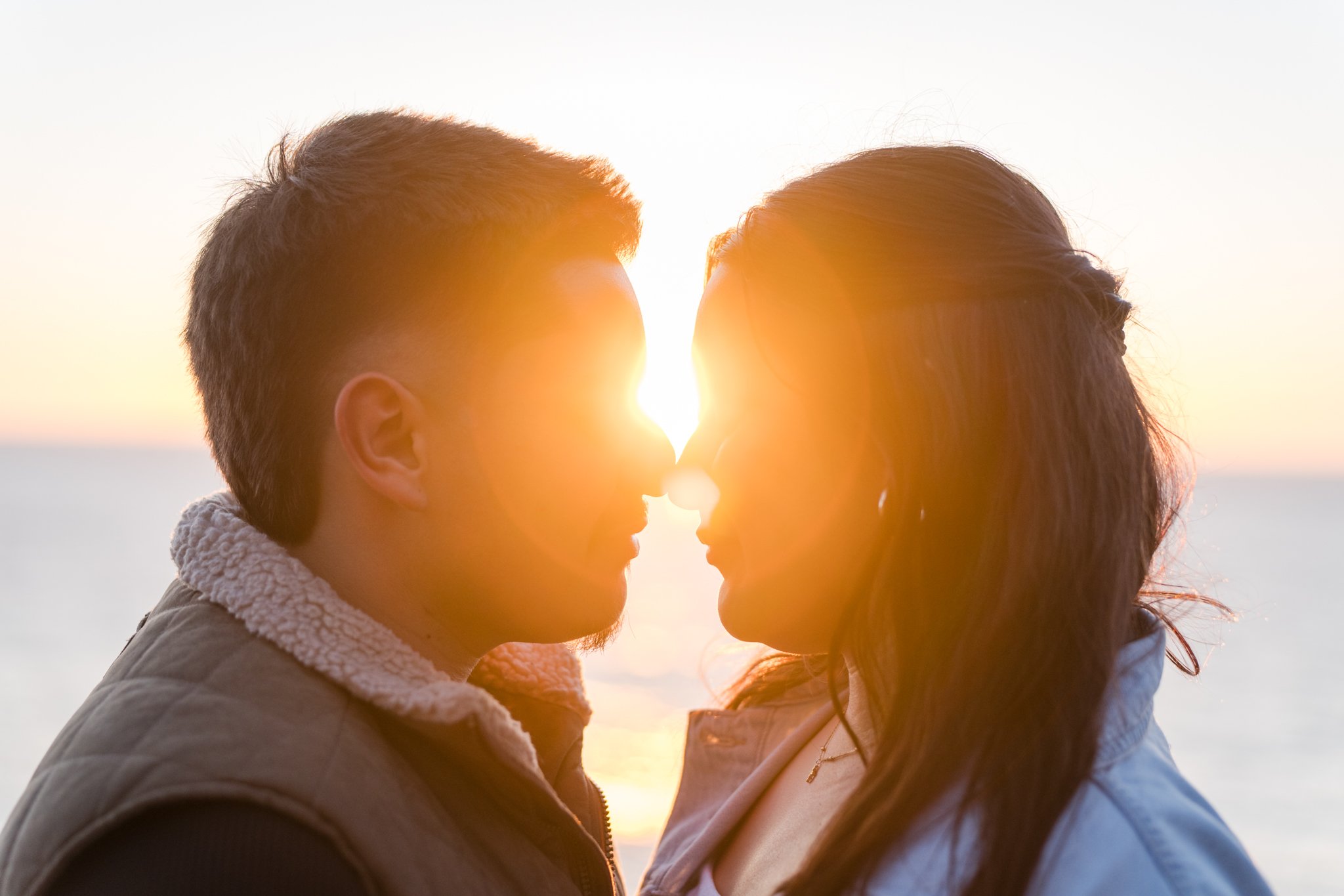 A couple standing face to face with the sun setting in the background, creating a beautiful silhouette