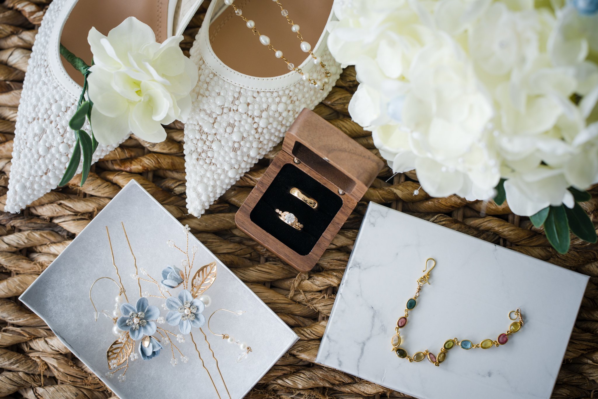 Flat lay of wedding details including invitation suite, rings, bouquet, and vow books from a Lincoln City micro wedding on the Oregon Coast.