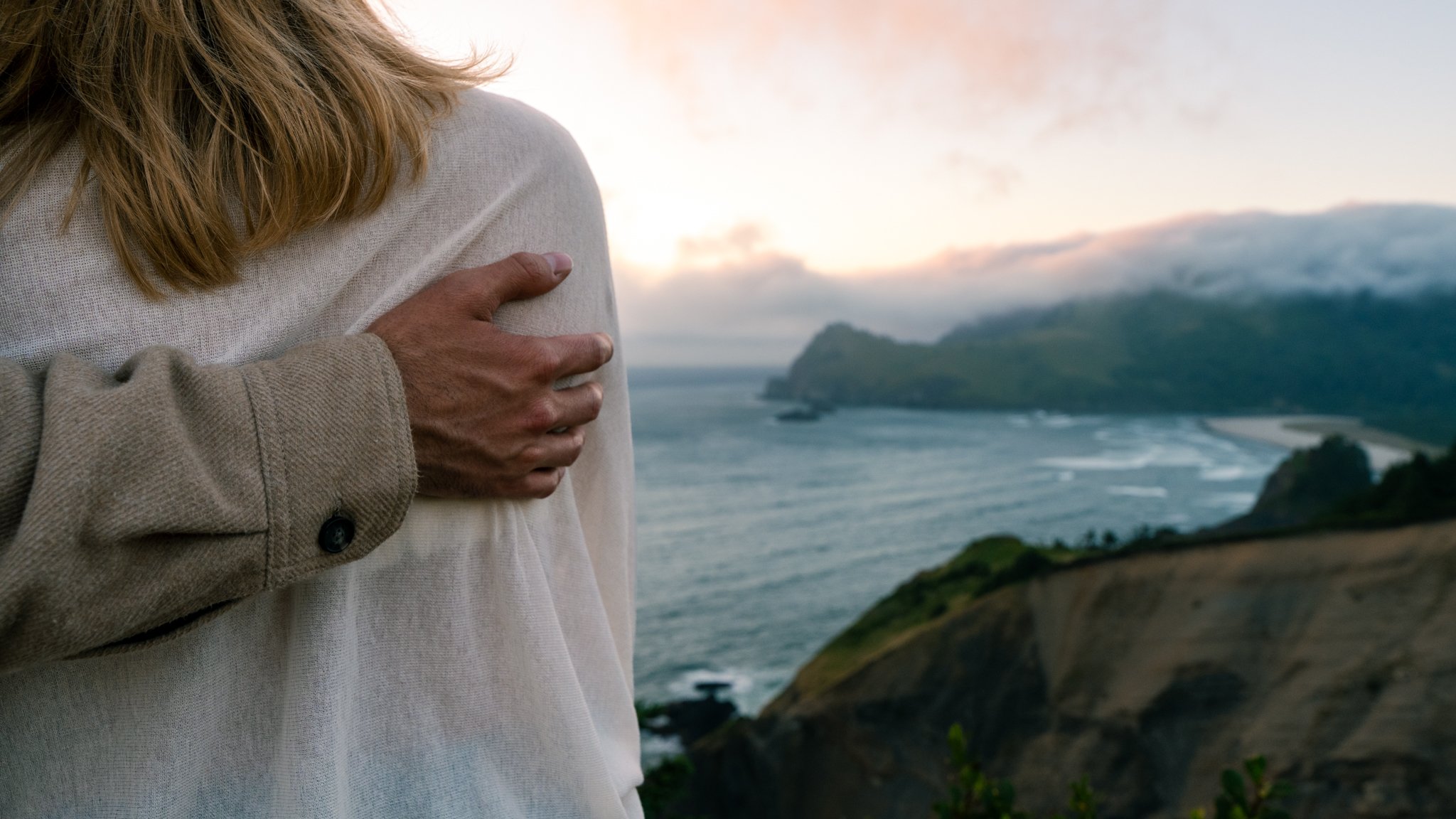 a couple looking over the ocean at the top of God's Thumb, with Cascade Head in the distance in lincoln city oregon